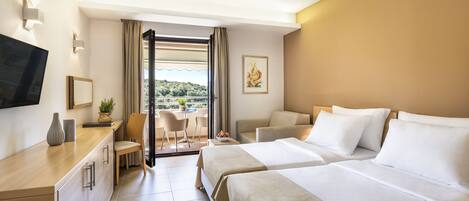 Habitación de hotel con dos camas, un escritorio con silla, televisión y balcón con vistas.