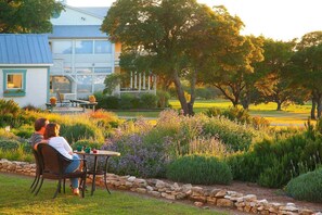 A couple sitting at a table in a garden with a house in the background. - Rose Hill Retreat (Fredericksburg)