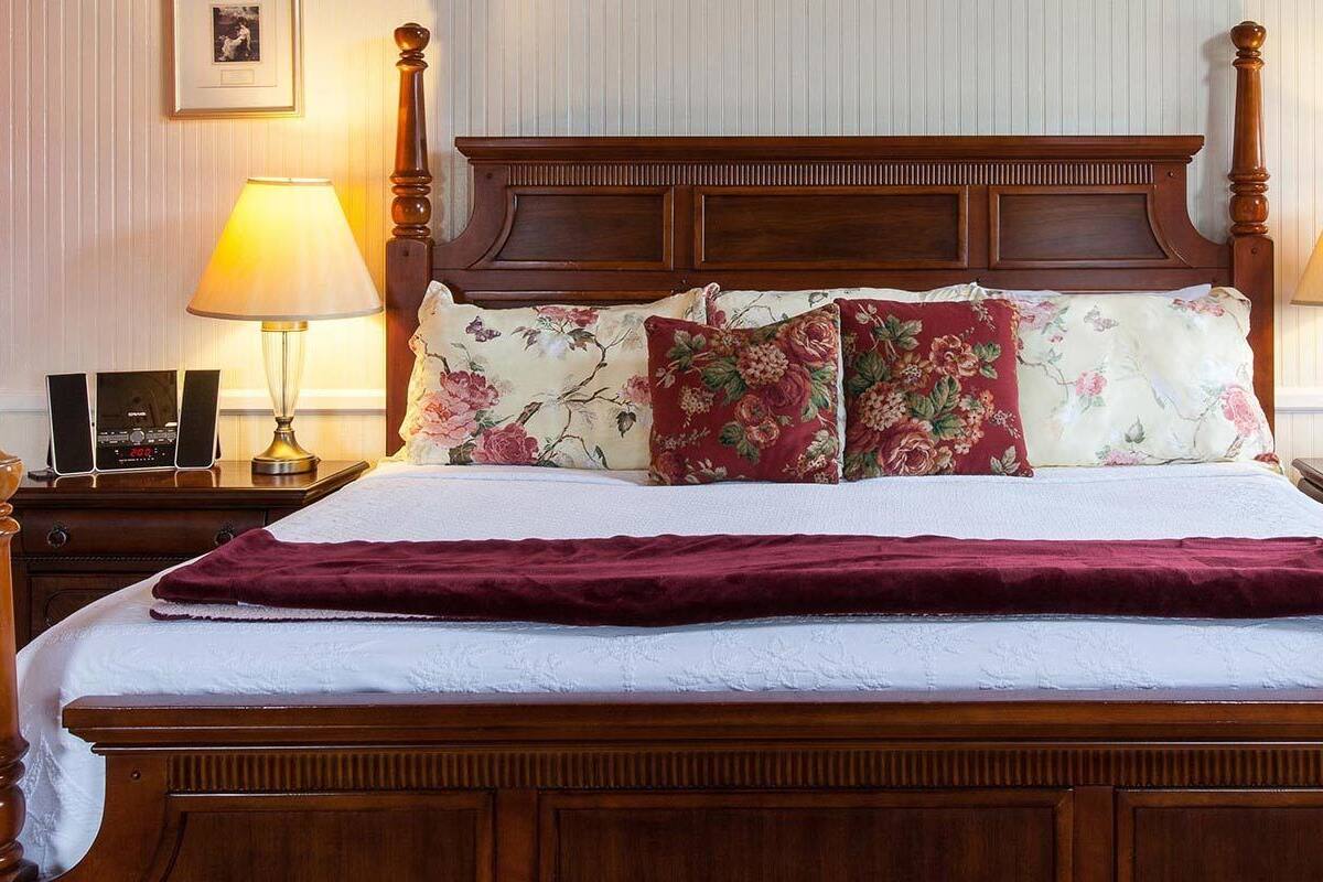 Ein Himmelbett mit floraler Bettwäsche und zwei Nachttischlampen.