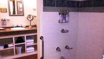 A bathroom with a sink, mirror, towel rack, and a shower with multiple faucets.