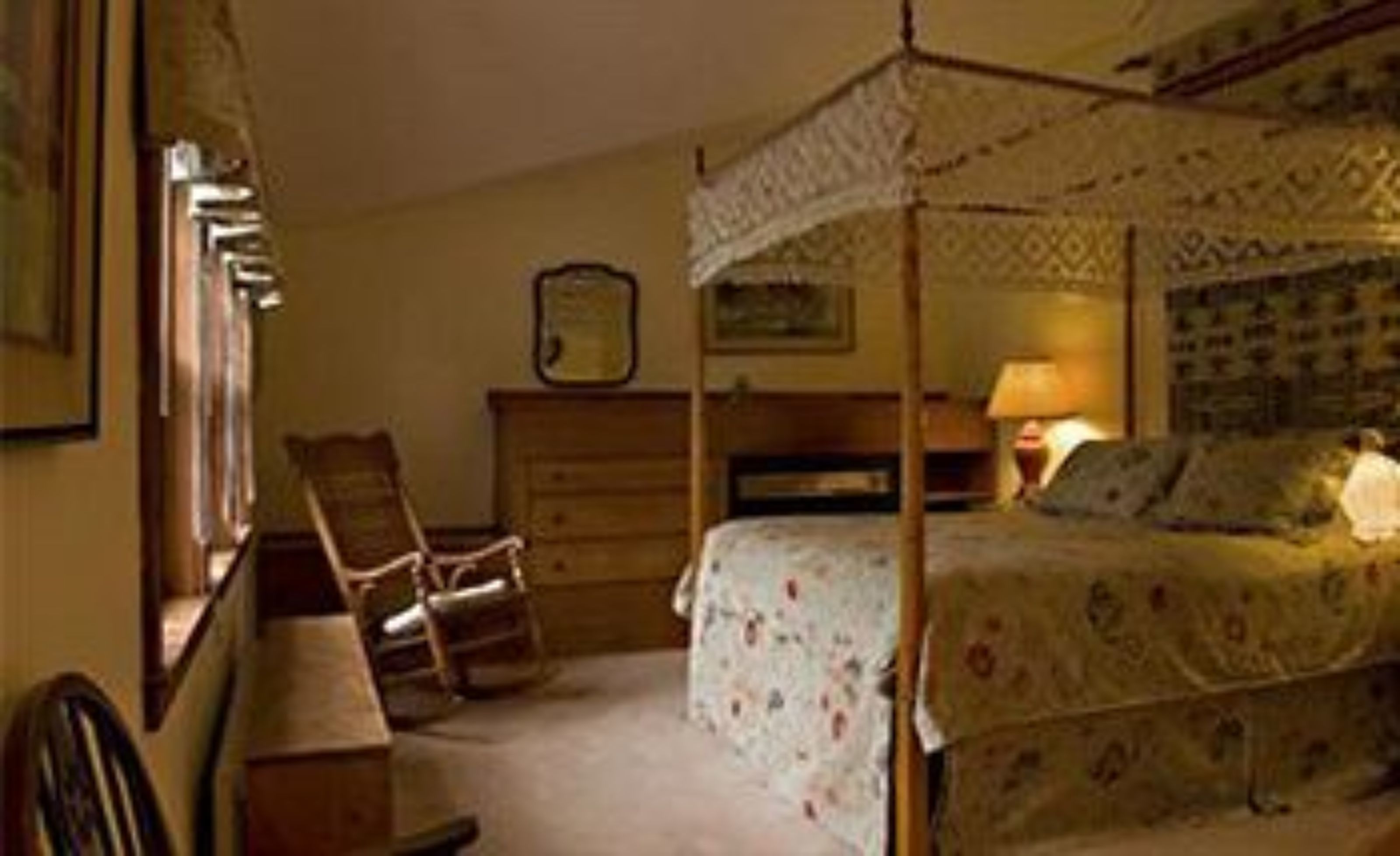 Une chambre à coucher avec un lit à baldaquin, une chaise, une commode et une table de chevet.