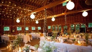 Ein Festsaal mit gedeckten Tischen für eine festliche Veranstaltung, mit Lichterketten und floralen Tischdekorationen.