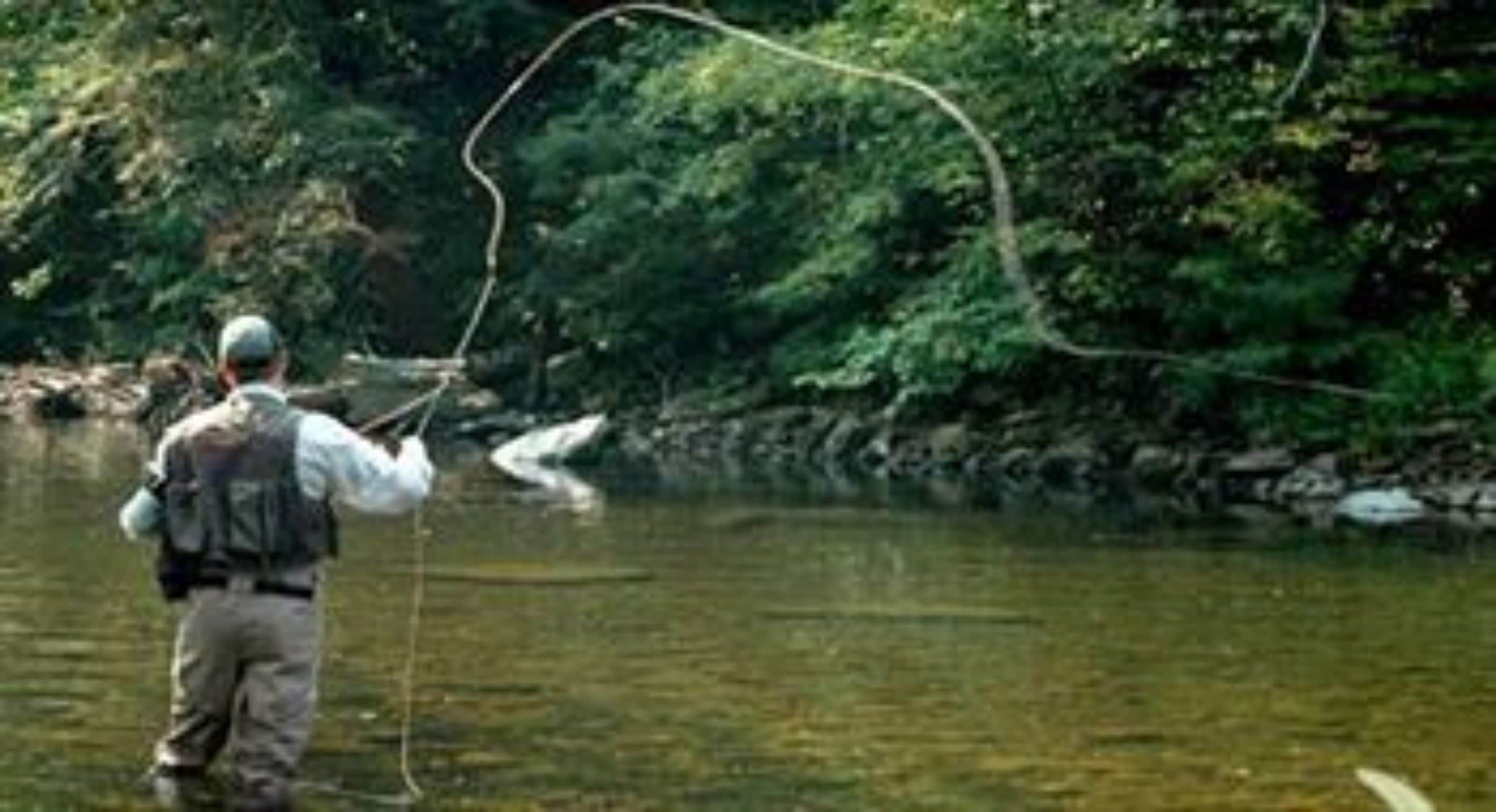 A person standing in a river, holding a fishing rod.