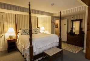 Restful retreat with a four-poster bed, nightstand, and dresser, set against a backdrop of vertical paneling and a patterned rug.