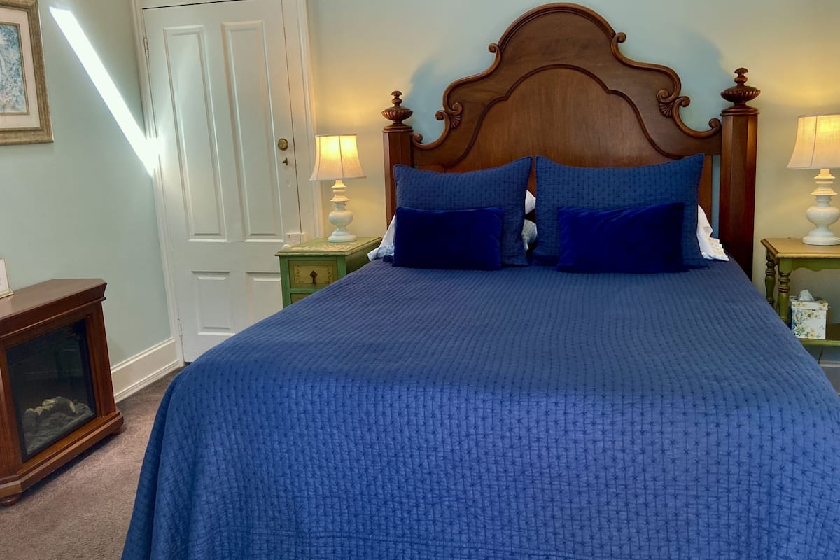 A bedroom with a large bed, two bedside lamps, a wooden headboard, and a door.