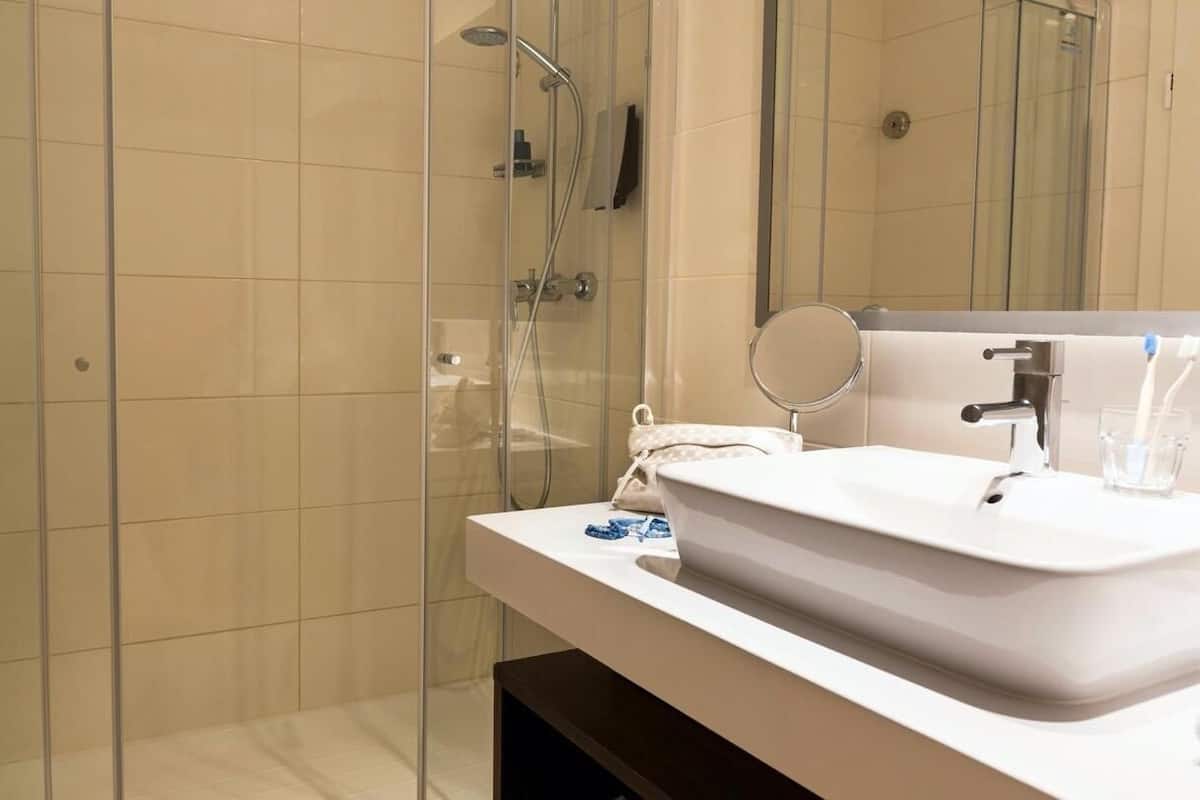 Une salle de bain moderne avec une douche à parois de verre, un lavabo blanc avec un miroir et un porte-serviettes.