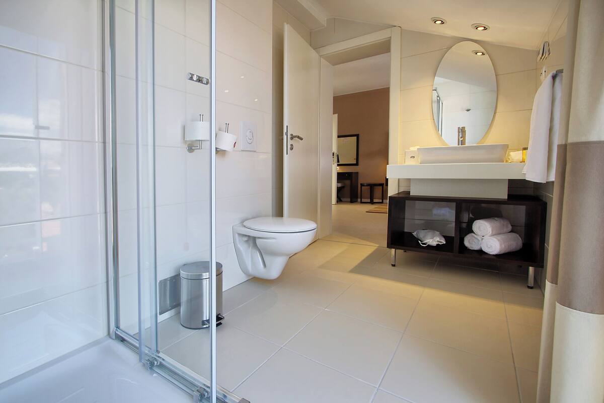 Une salle de bain moderne avec une douche à parois de verre, des toilettes blanches, un lavabo avec un miroir et un porte-serviettes.