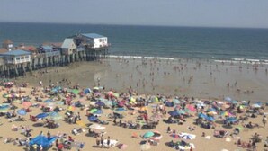 Una playa con un muelle y gente caminando.