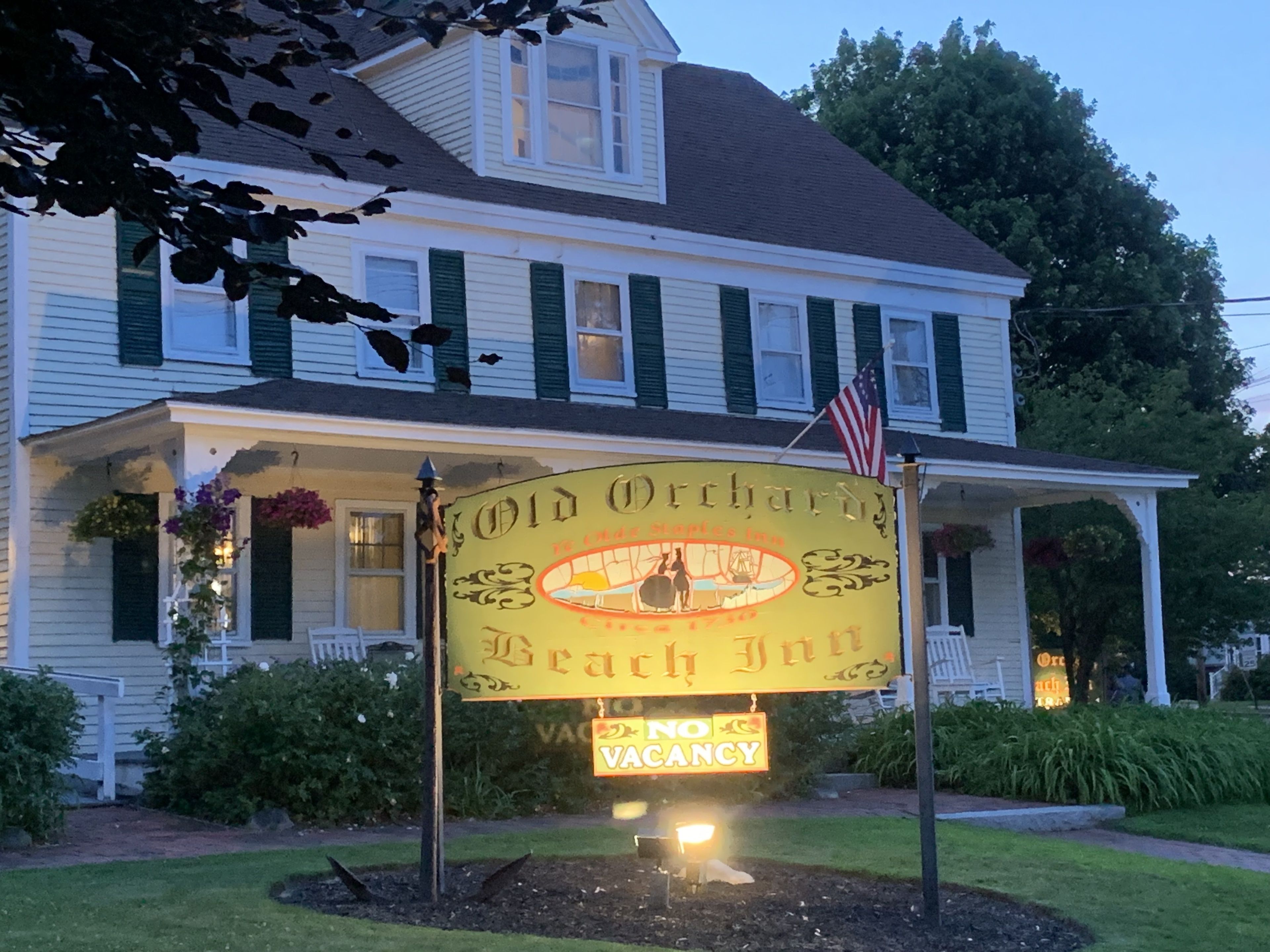 A two-story building with a porch, a sign for 'Old Orchard Beach Inn', and a 'No Vacancy' sign.