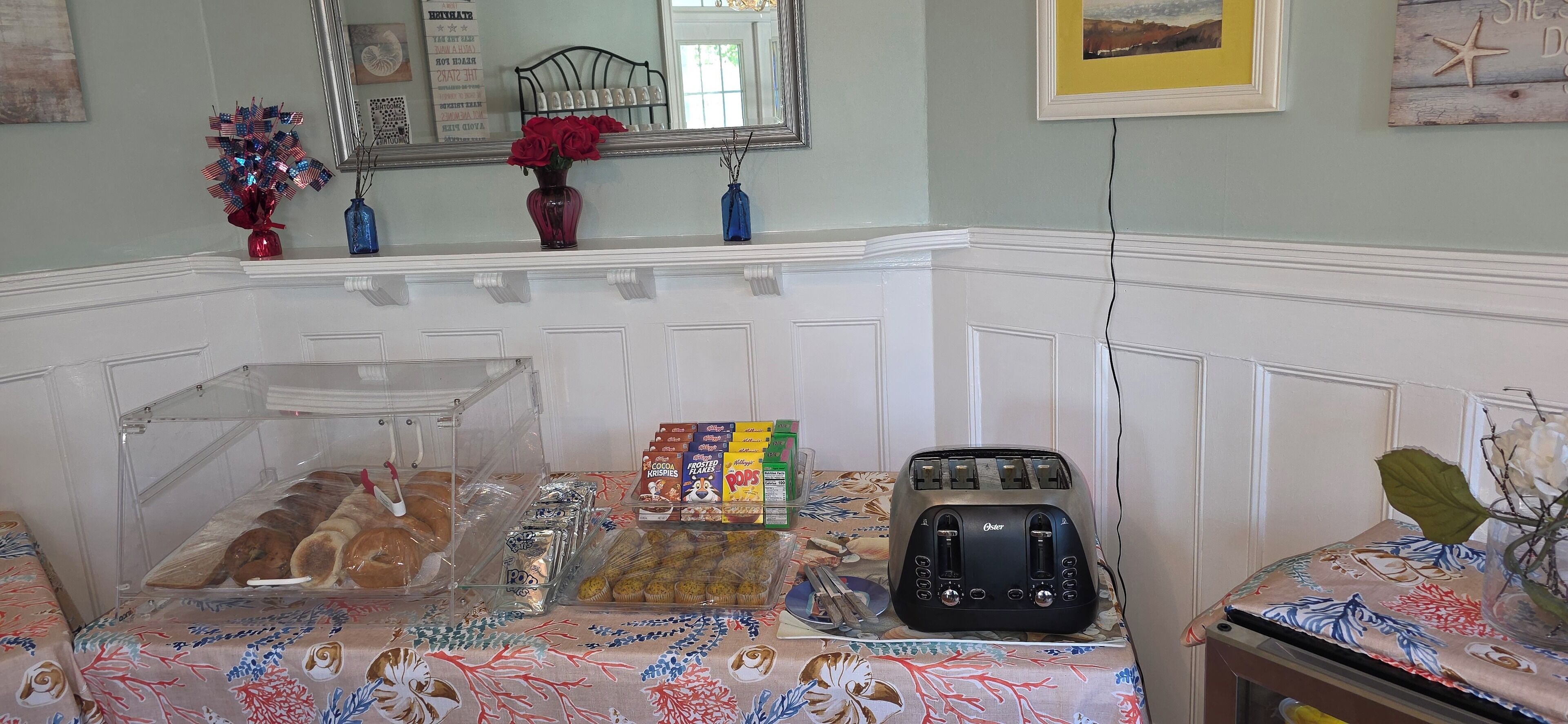 A room with a kitchenette area, including a toaster, a variety of packaged food items, and a decorative mirror.