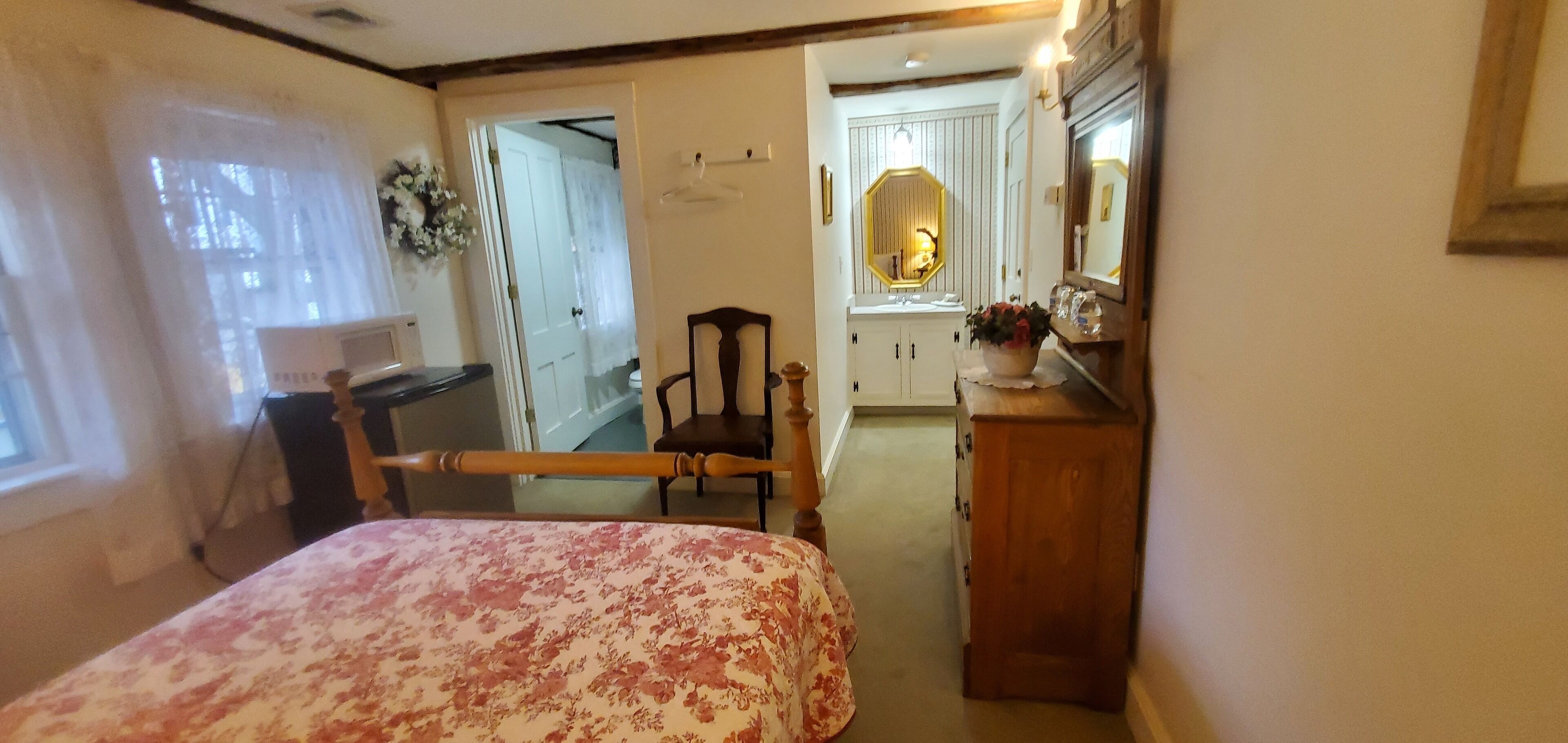 A bedroom with a bed, a chair, a dresser, and a mirror.