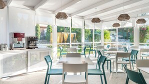Cafetería luminosa y de espacio abierto con muebles modernos y amplias ventanas que ofrecen vistas al exterior.