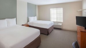 A hotel room with two beds, a TV, and a window with blinds. - WoodSpring Suites Jacksonville Beach Blvd (Jacksonville)