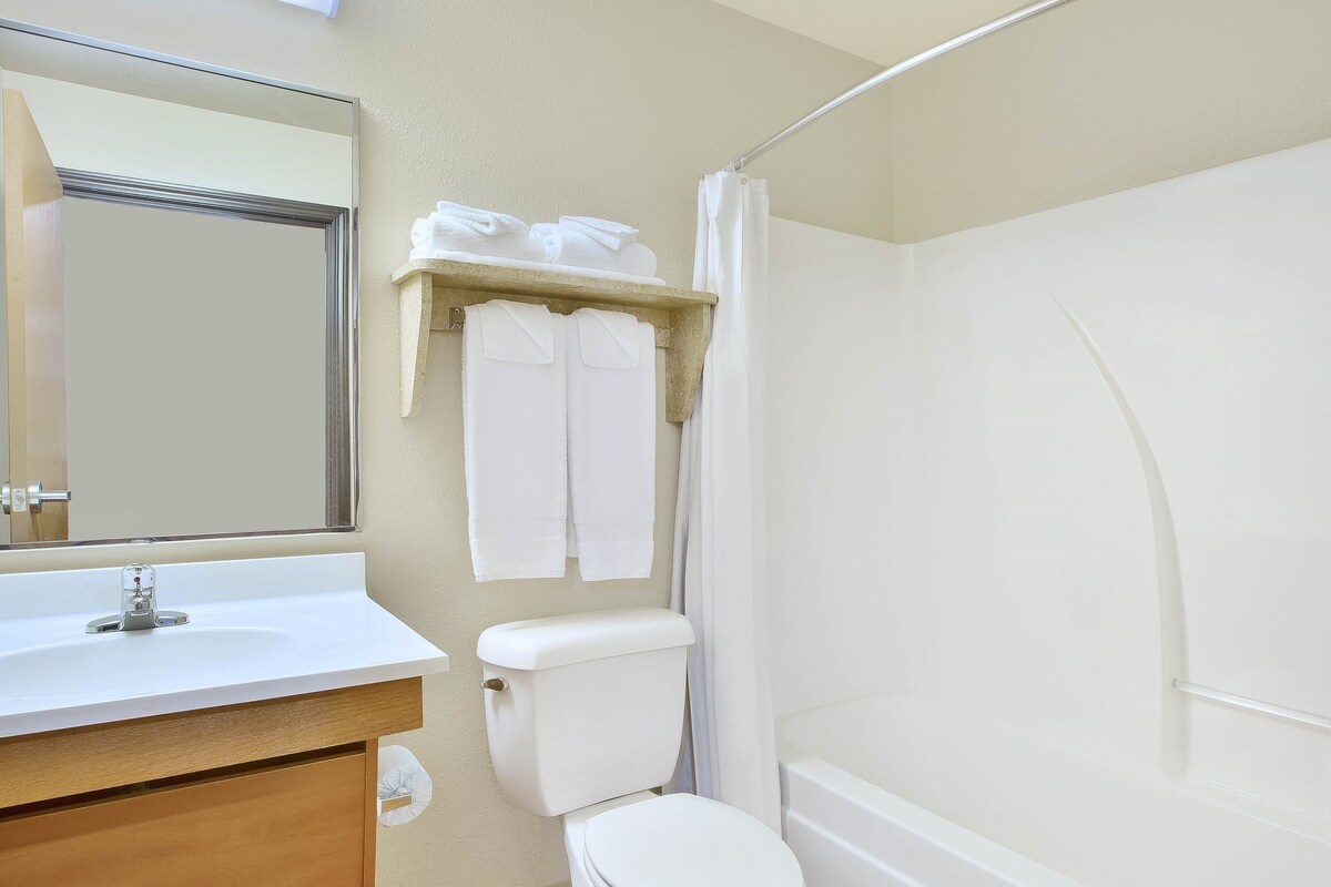 A bathroom with a white sink, toilet, and bathtub. There is a towel rack with folded towels above the toilet.