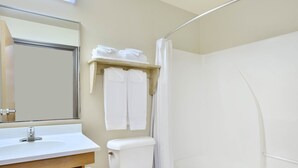 A bathroom with a white sink, toilet, and bathtub. There is a towel rack with folded towels above the toilet.
