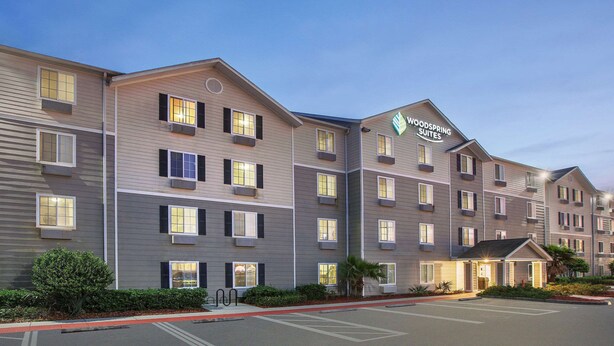 A multi-story hotel with a modern design, featuring a prominent sign for 'Woodspring Suites'. - WoodSpring Suites Jacksonville Beach Blvd (Jacksonville)