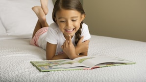 A child lying on a bed reading a book.