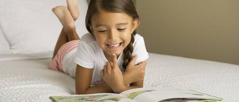 A child lying on a bed reading a book.