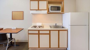 A compact kitchenette with a microwave, sink, and refrigerator. - WoodSpring Suites Jacksonville Beach Blvd (Jacksonville)
