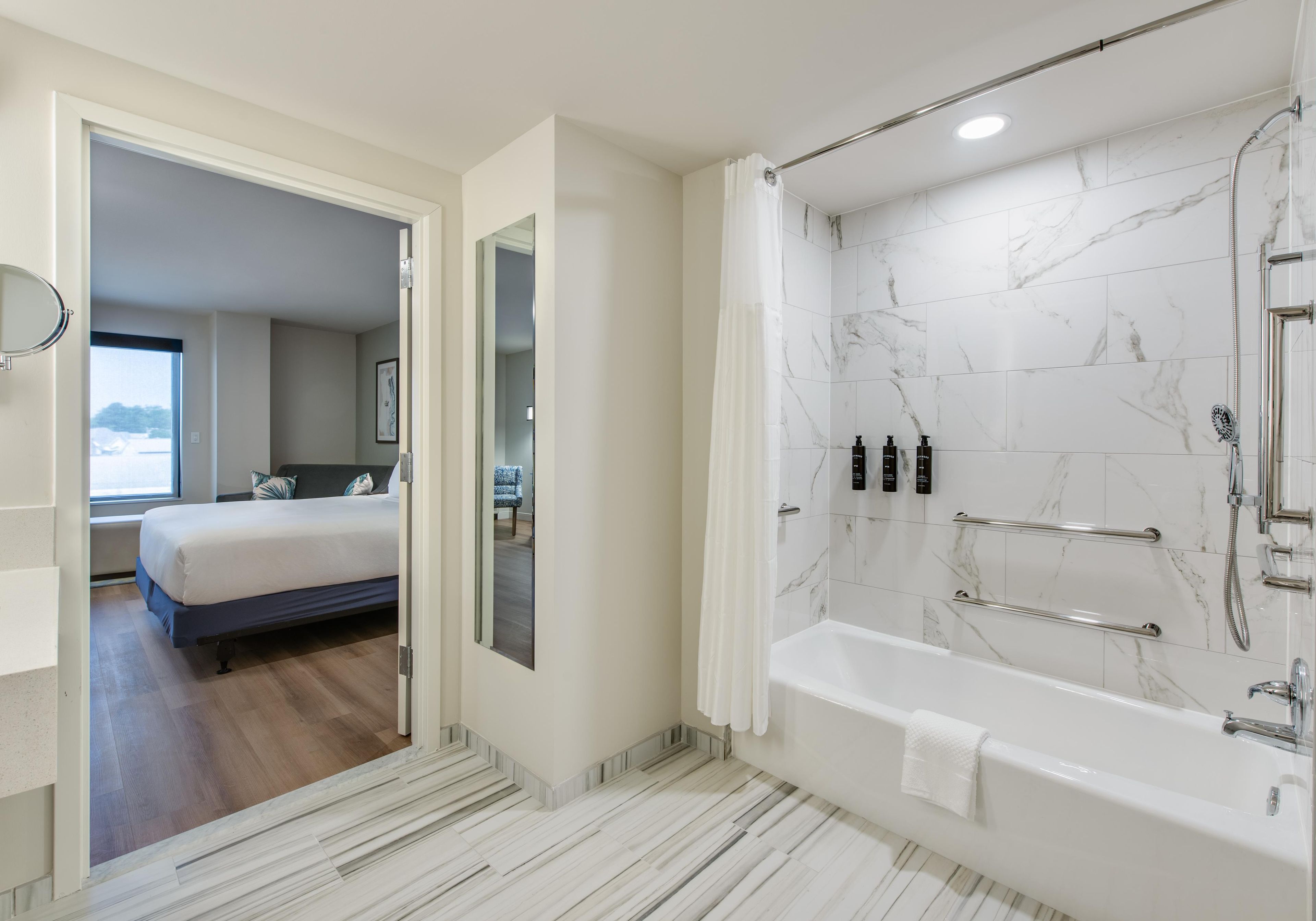 A modern bathroom with a marble shower, a bathtub, and a visible shower head.