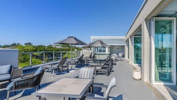 A rooftop terrace with outdoor seating, a glass-enclosed area, and a clear view of the sky.