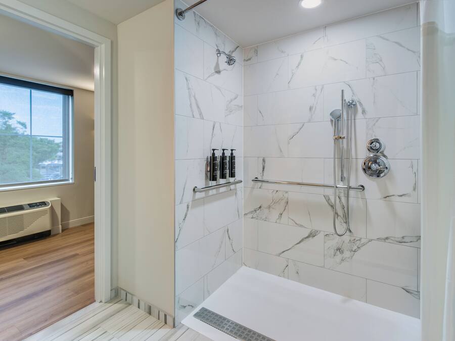 Un baño moderno con ducha a nivel, baldosas de mármol, ventana y calefacción integrada.