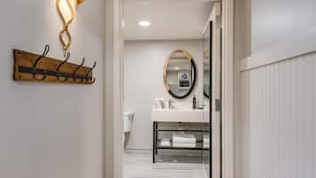 A hallway leading to a bathroom with a white toilet, a towel rack, and a mirror.