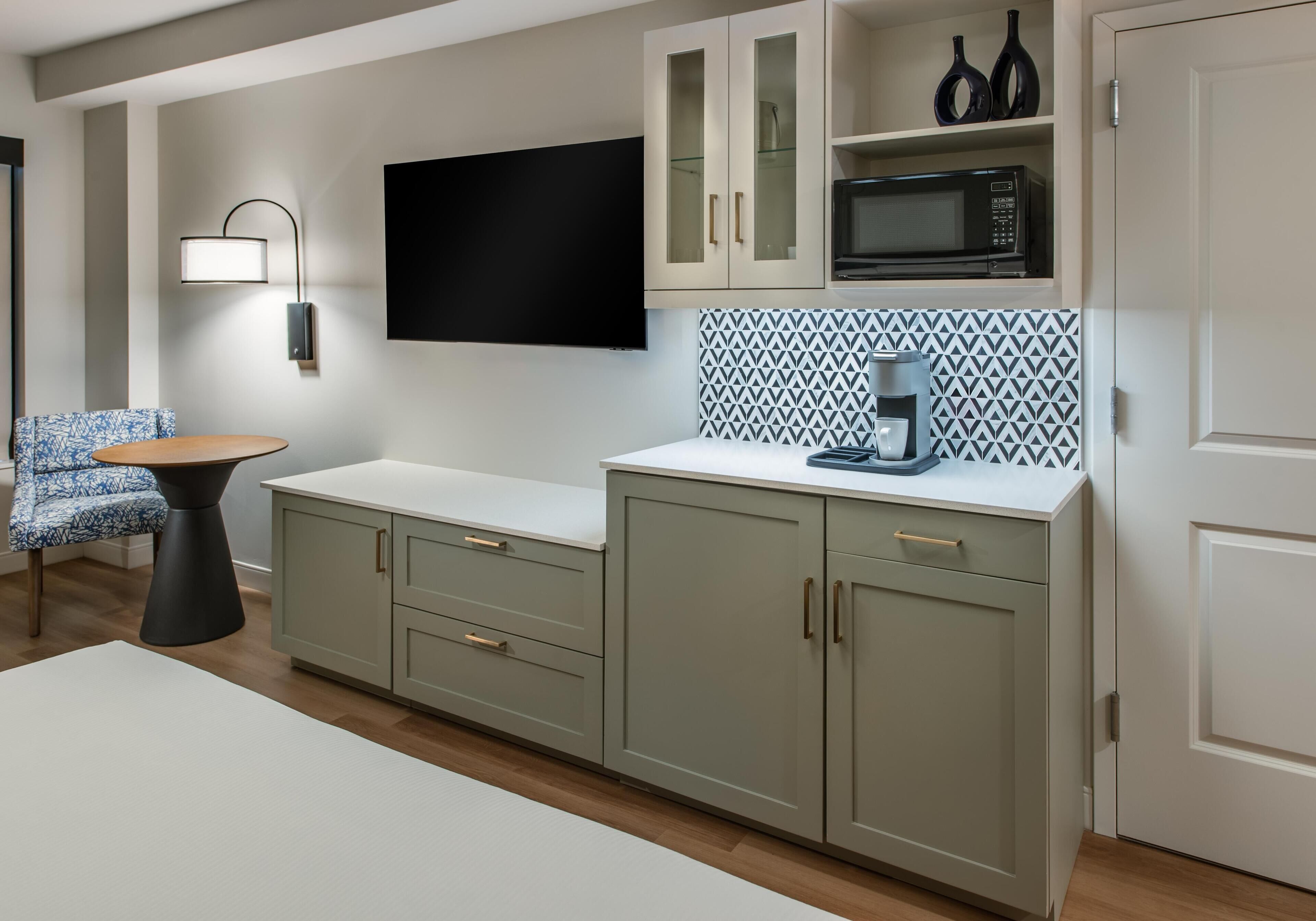 Una cocina moderna con televisión de pantalla plana, microondas y salpicadero con diseño.