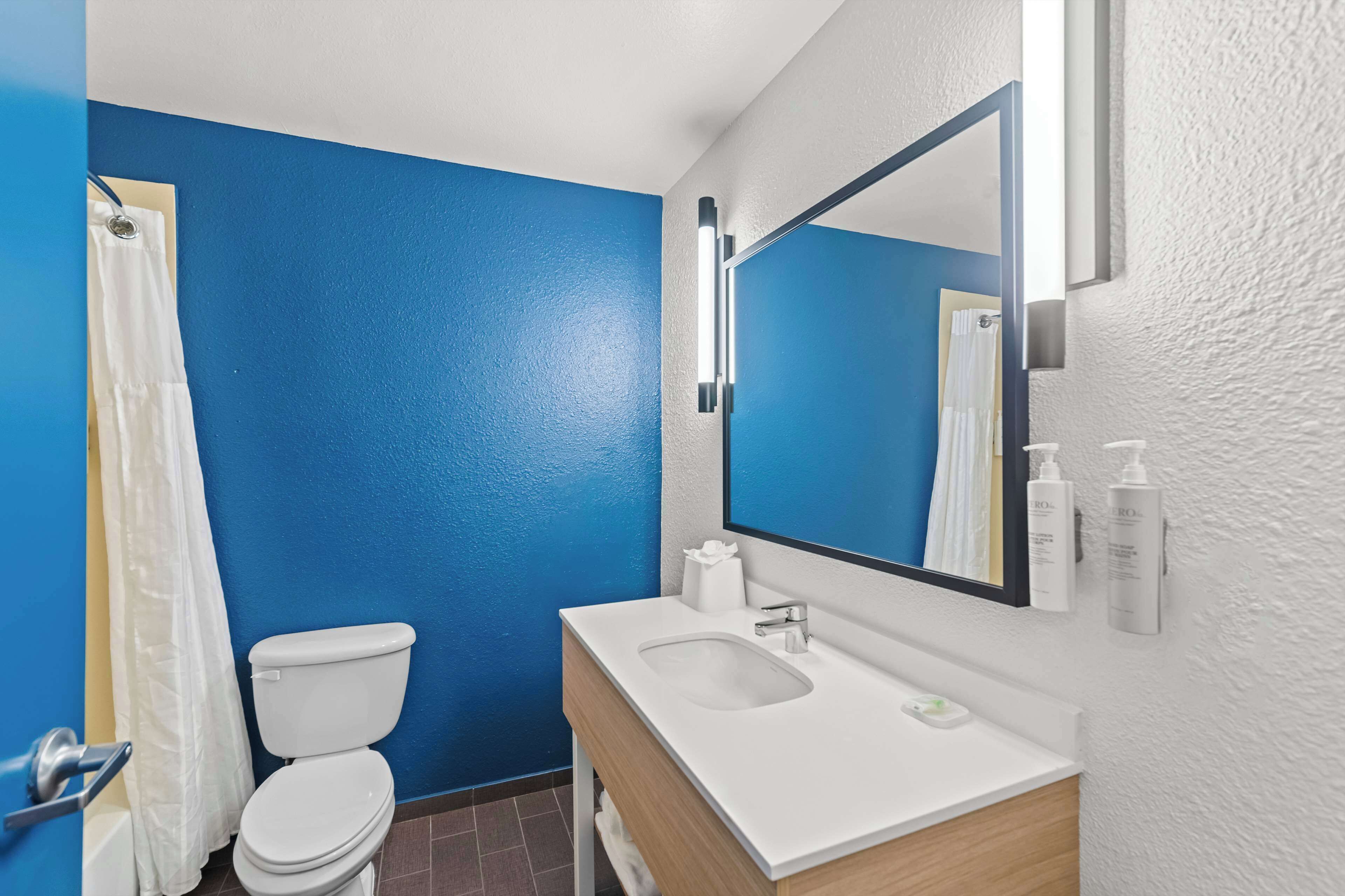 Une salle de bain avec un mur bleu, un lavabo blanc et des toilettes.