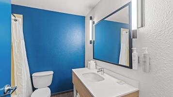 Une salle de bain avec un mur bleu, un lavabo blanc et des toilettes.