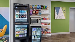 Un área de venta con diferentes aperitivos y bebidas, un microondas y un refrigerador.