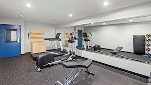 Un gimnasio con equipo de ejercicio, un espejo y una puerta.