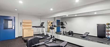 A gym with exercise equipment, a mirror, and a door.