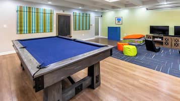 Une table de billard dans une pièce avec un plancher en bois, un mur bleu et une porte.