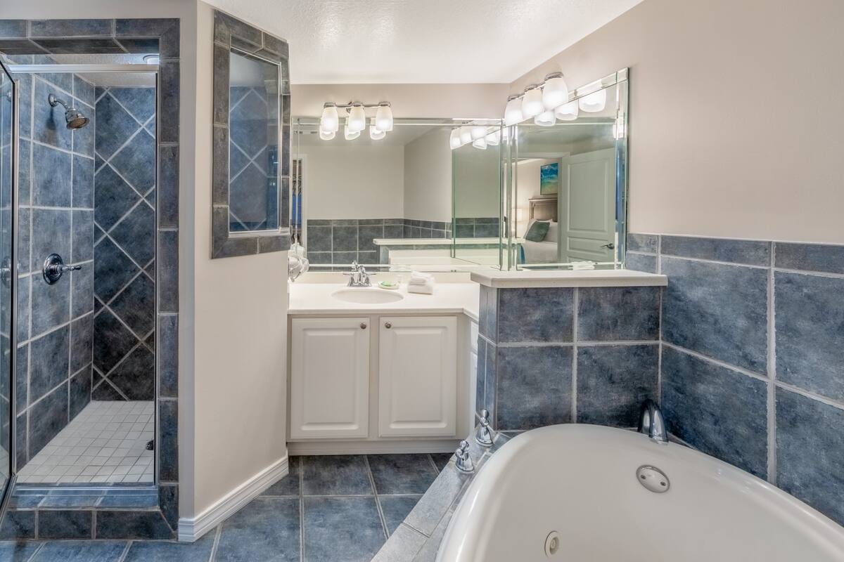 Un baño moderno con ducha a ras de suelo, una bañera independiente y un tocador con espejo.