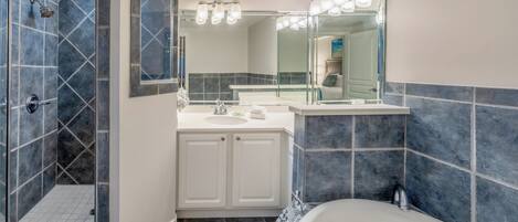 A modern bathroom with a walk-in shower, a bathtub, and a vanity with a mirror.