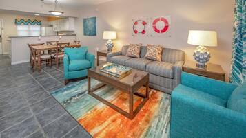 A living room with a sofa, two armchairs, a coffee table, and a dining area with a table and chairs.