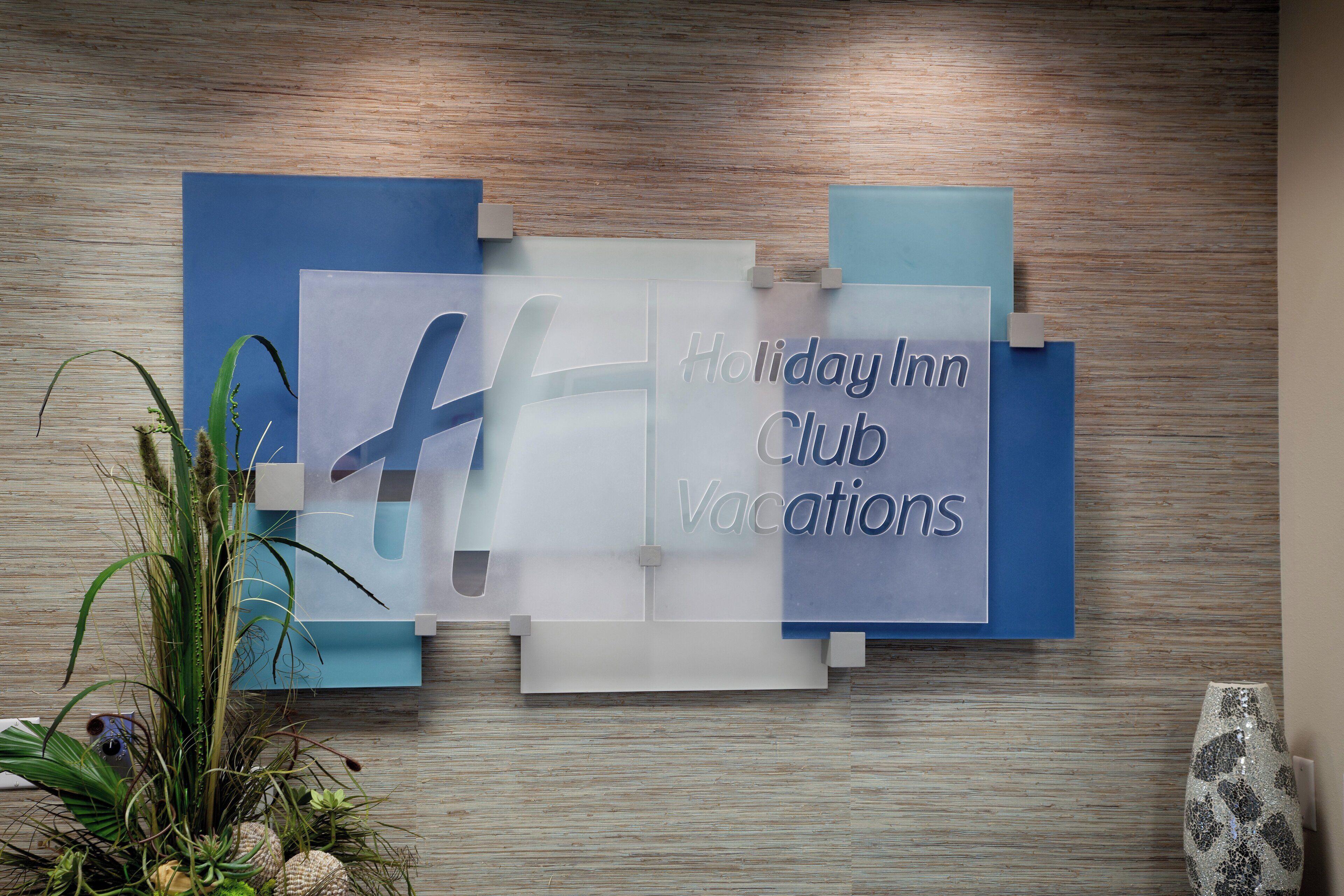 Una pared con un letrero de 'Holiday Inn Club Vacations' y una planta decorativa.