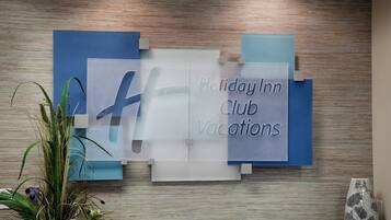 Una pared con un letrero de 'Holiday Inn Club Vacations' y una planta decorativa.