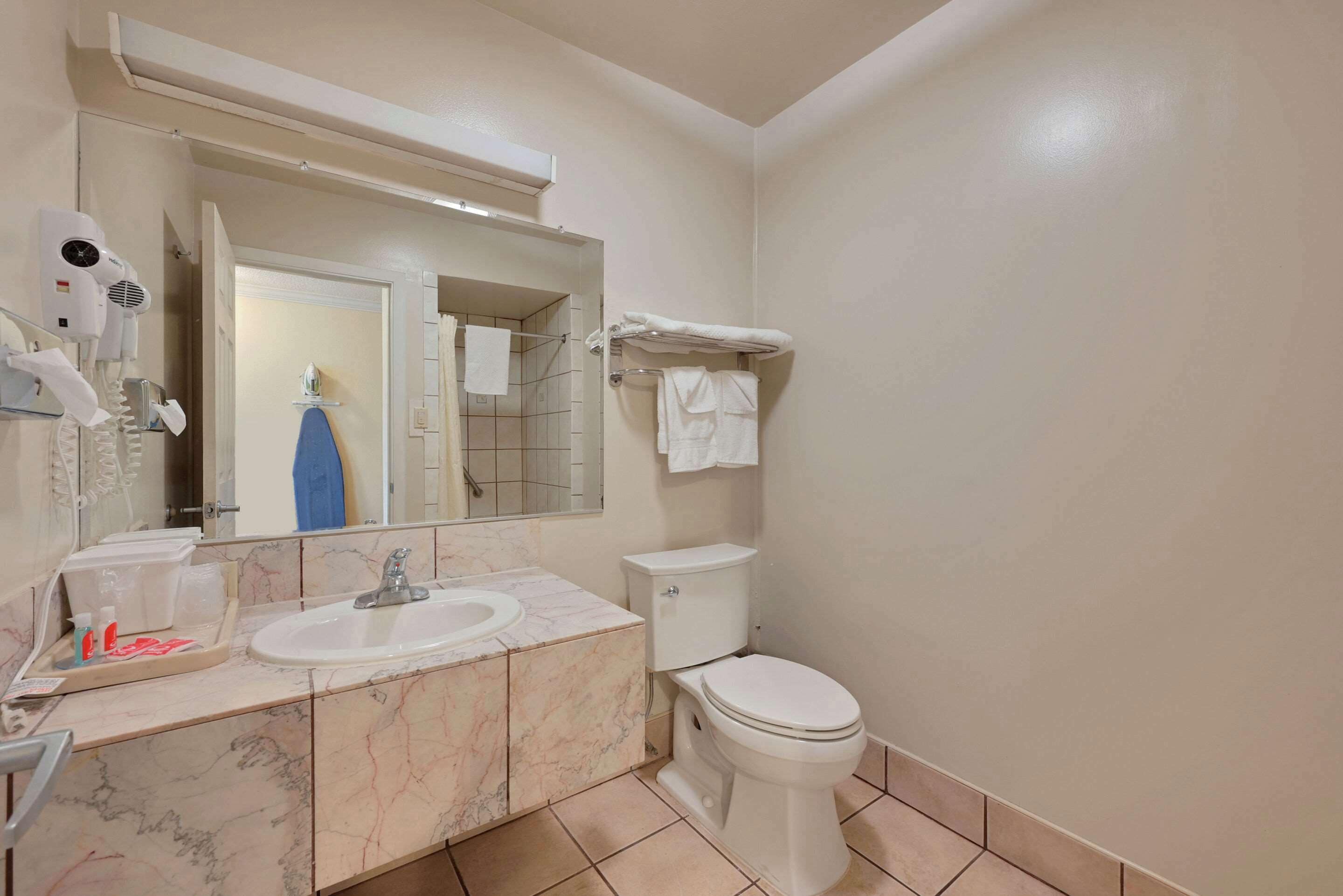 Baño con lavamanos, espejo, secador de pelo y retrete.