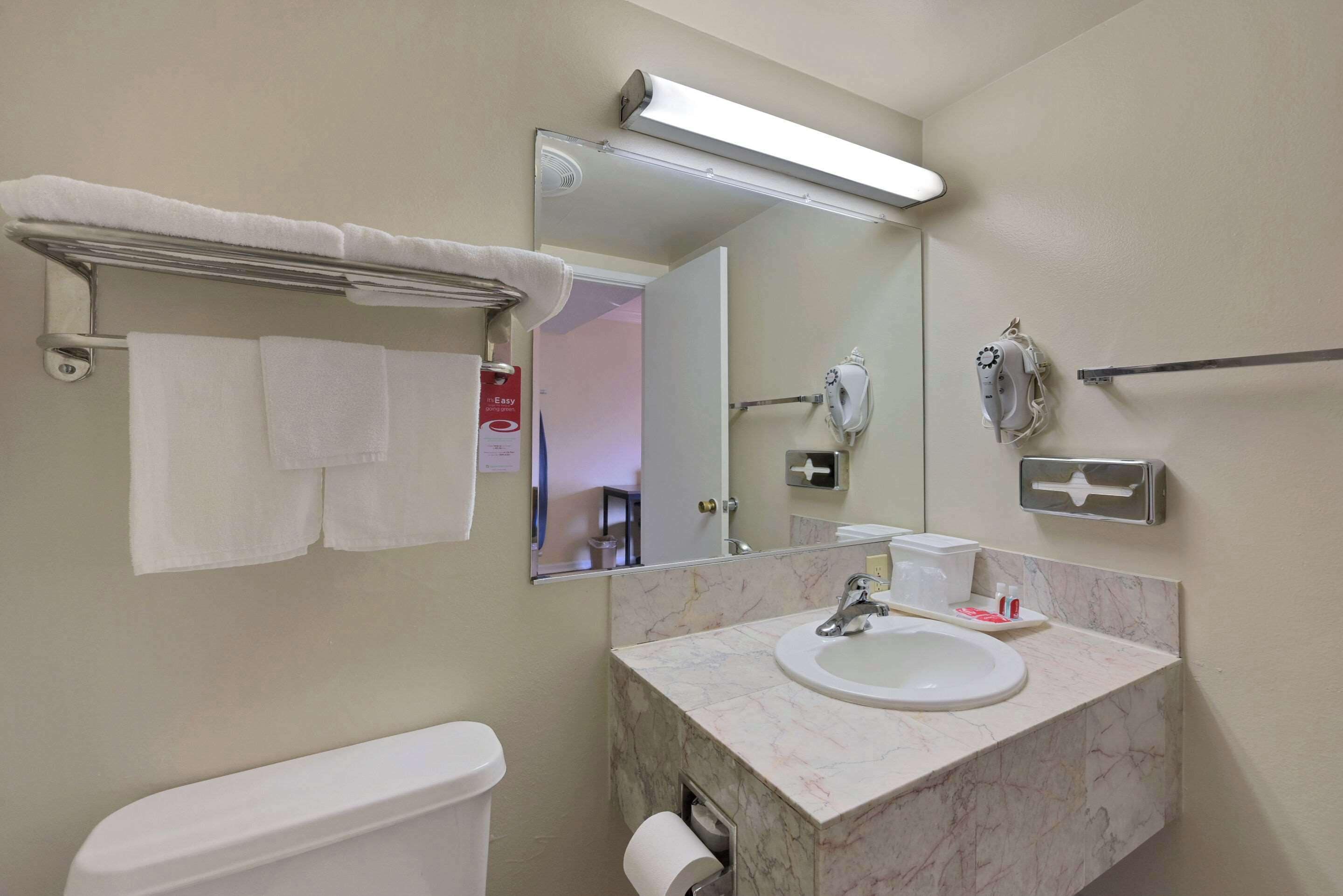 Un baño con inodoro, lavabo, espejo y toallero.