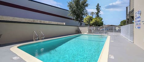 Una piscina rectangular con borde blanco, barandillas de metal y superficie de agua azul cristalina.