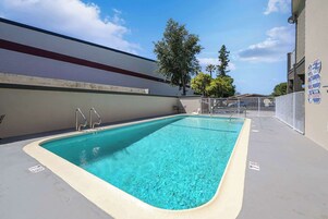 Una piscina rectangular con borde blanco, barandillas de metal y superficie de agua azul cristalina.