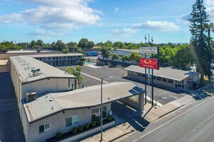 Un hotel con un letrero que dice "Welcome to Woodland" y "EconoLodge". Cuenta con un estacionamiento, una piscina y un edificio de techo inclinado.