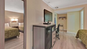 Habitación de hotel con dos camas, un escritorio con computadora, una silla y un espejo.