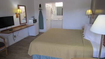 Ein Hotelzimmer mit Bett, Schreibtisch, Fernseher, Mikrowelle und kleinem Kühlschrank.
