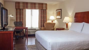 A hotel room with a bed, desk, chair, and two lamps.