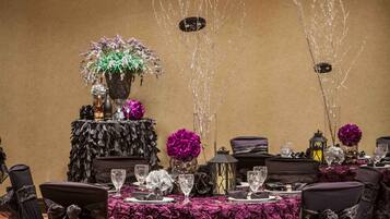 A banquet table set with chairs, a floral centerpiece, and decorative lighting.