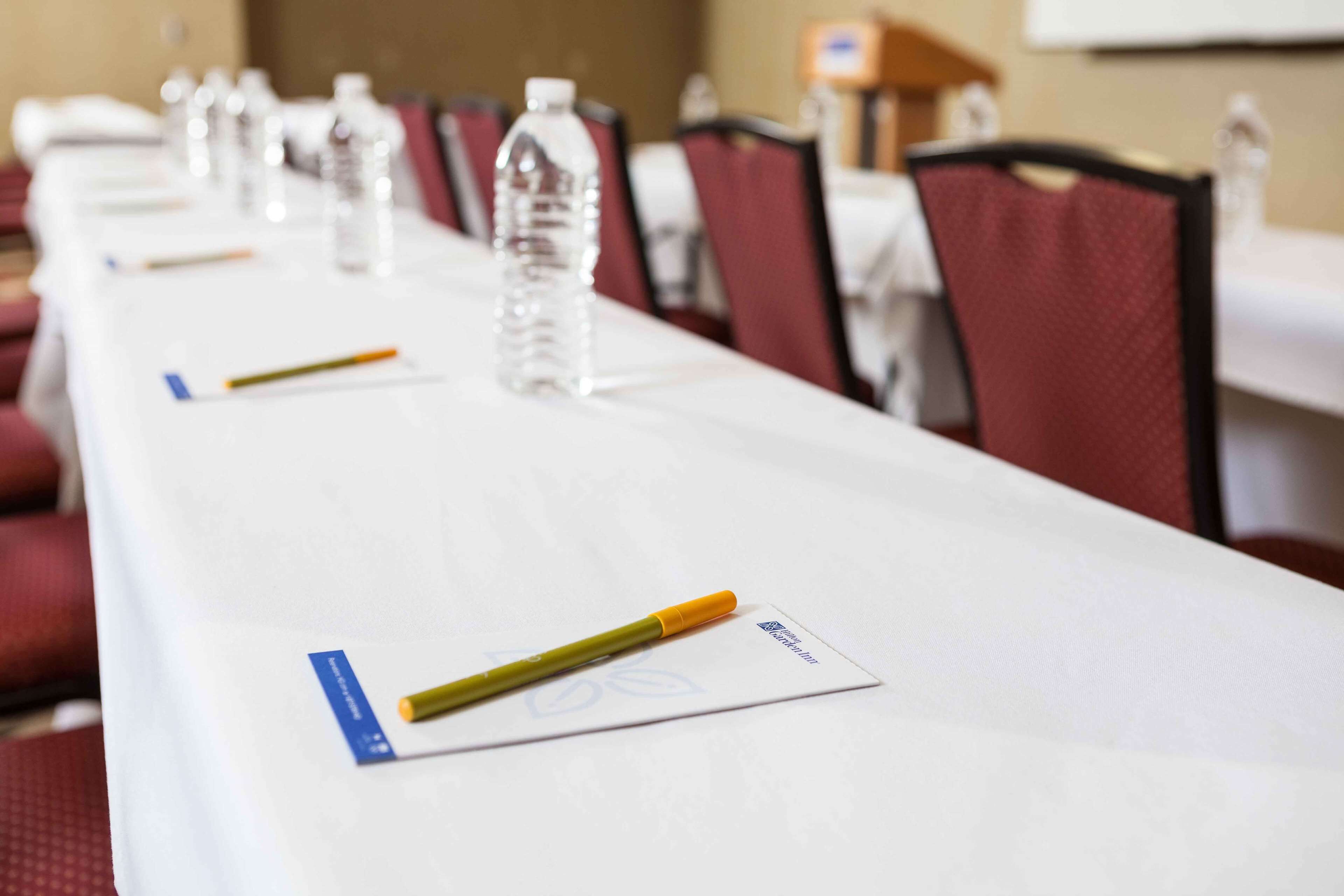 Una mesa de conferencias con botellas de agua, bolígrafos y tarjetas de identificación.