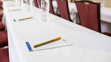 Una mesa de conferencias con botellas de agua, bolígrafos y tarjetas de identificación.